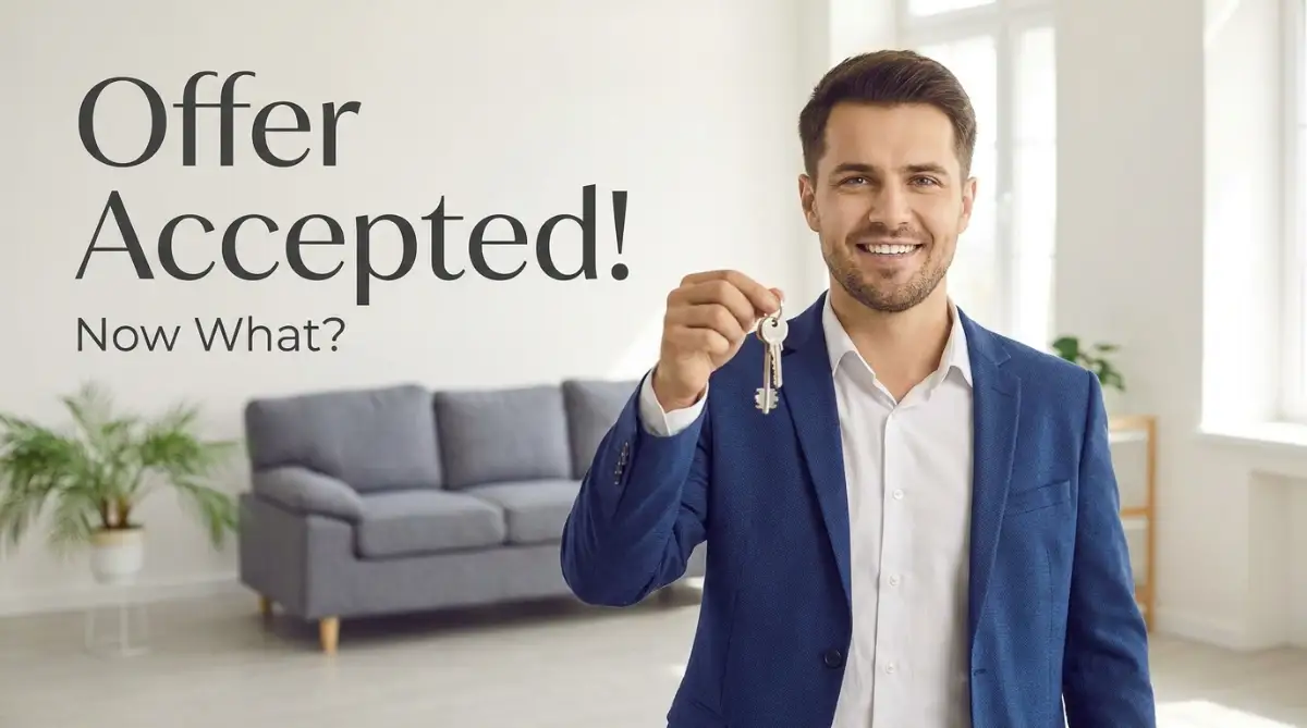 A smart young man smiling and holding house keys in a bright room, representing exactly what happens after your offer gets accepted on a house.
